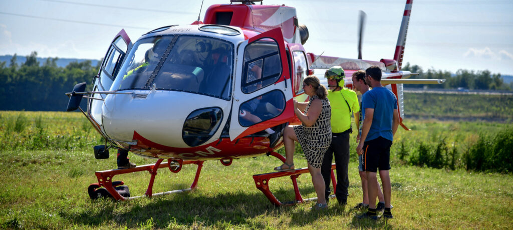Passagiere steigen in einen weiß roten Helikopter vom Typ AS350 der Fima Hubifly ein