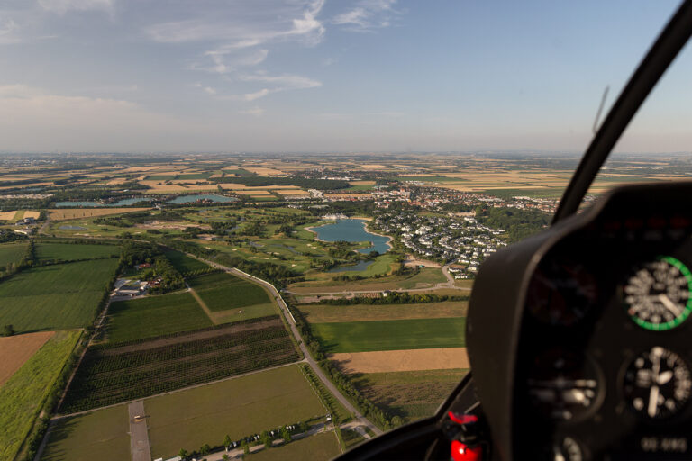 Foto aus dem Cockpit von einem Rundflug in Niederösterreich. Zu sehen sind grüne Felder und Seen.