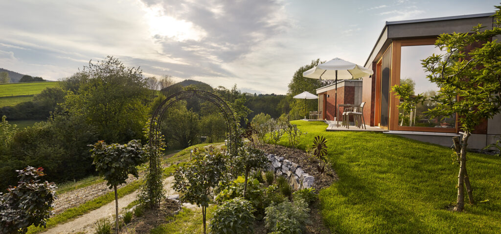 Aussenaufnahme vom Triad-Machreich. Gartenanlage mit Bäumen und grüner Wiese.