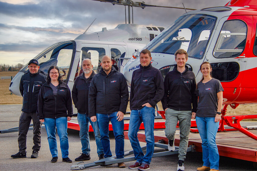 HubiFly Team, 7 Personen und 2 Helikopter im Hintergrund