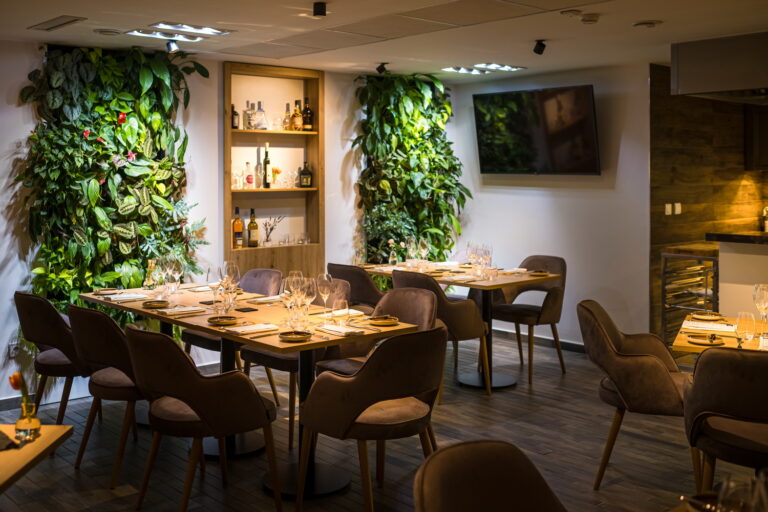 Eleganter Chefs Room im Kistücsök Food & Room mit stilvoll gedeckten Tischen, modernen Polsterstühlen und vertikalen Pflanzenwänden.