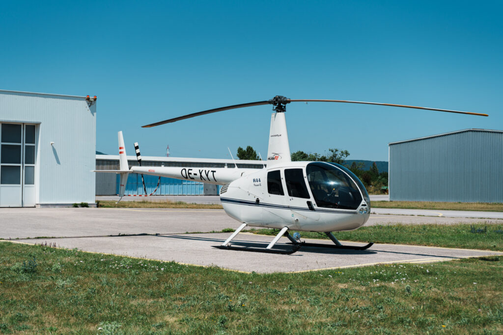 Schrägaufnahme Robinson R44 Raven II in weiß am Vorfeld