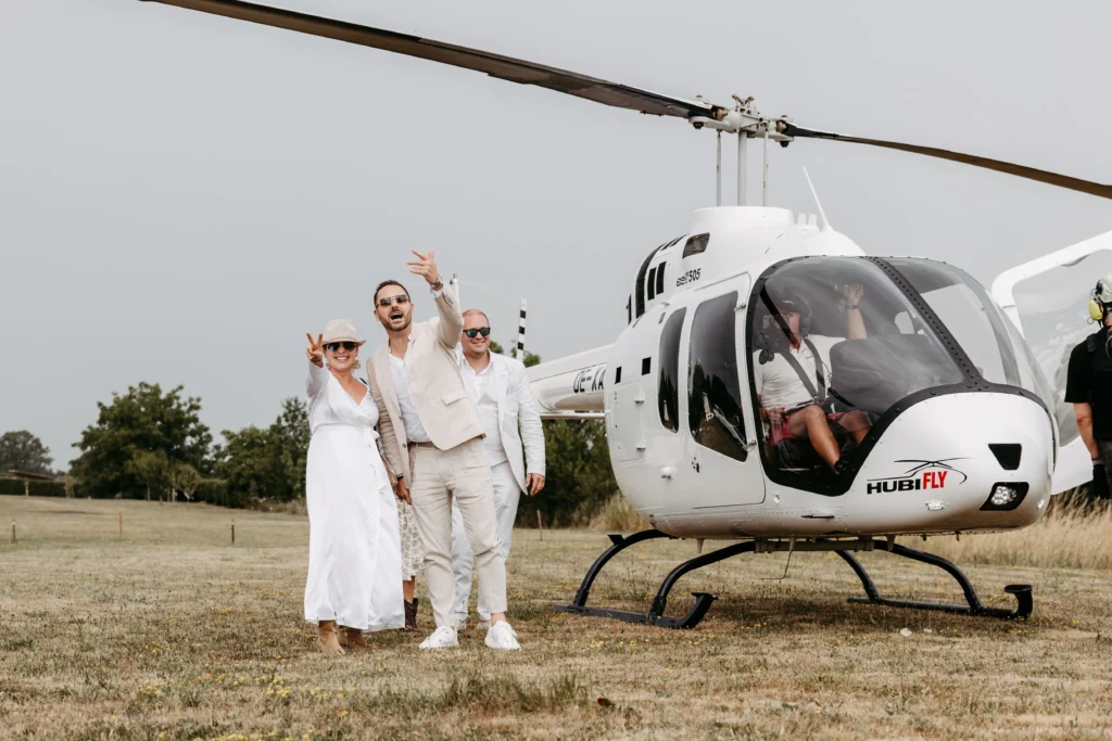 Braut und Bräutigam neben einem Hubschrauber auf einem Feld.