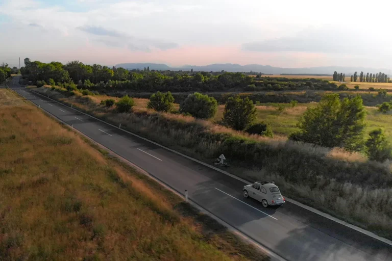 Ein Auto fährt auf einer Landstraße mit Cinematischen Hintegrund