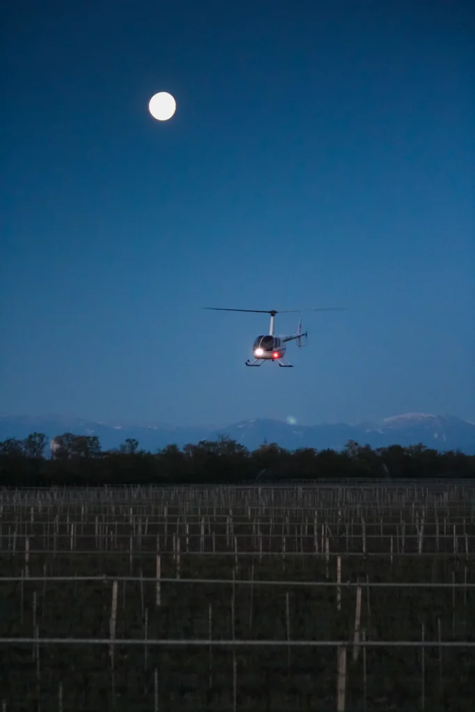 Hubschrauber im Morgengrauen über Weinfelder.