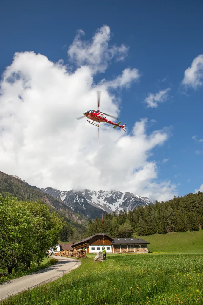 Hubschrauber beim Transport von einer Aussenlast zu einer Berghütte