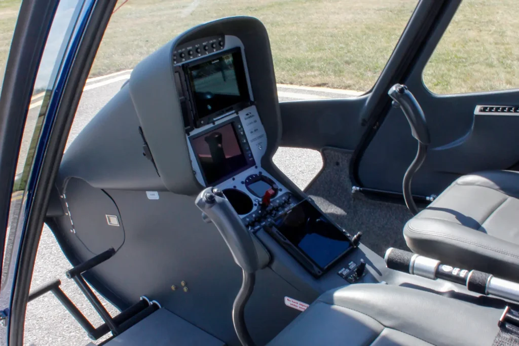 Interior of a small aircraft cockpit with dual screens and flight controls visible by the pilot seat.